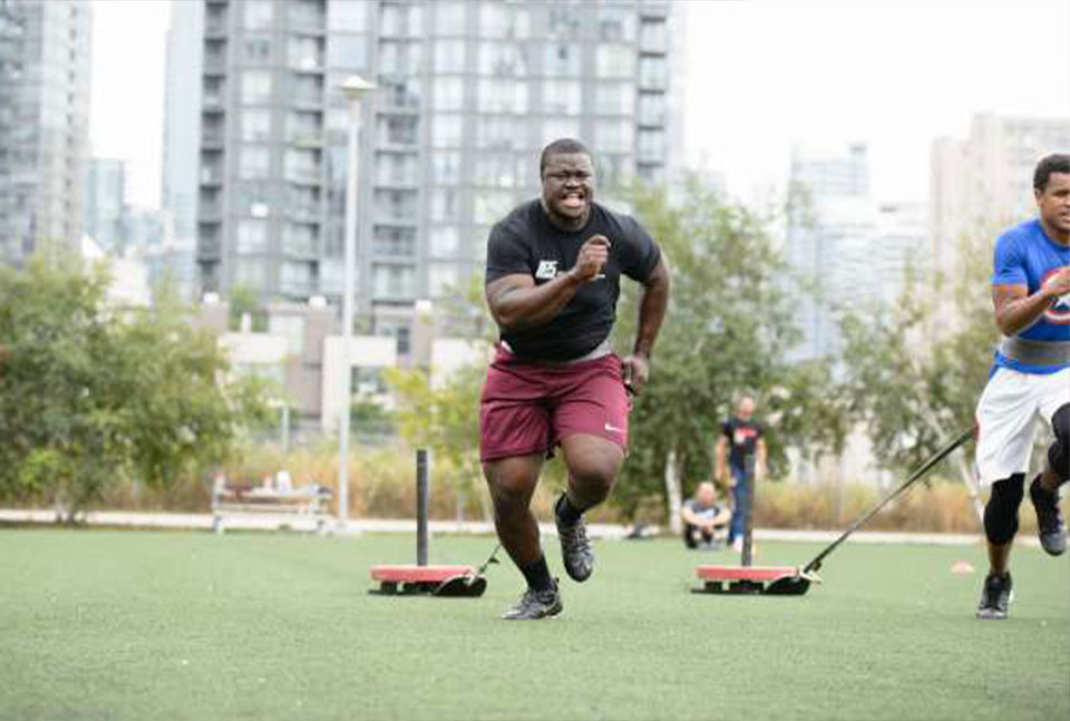 A photo of Fabion Foote doing sled sprint with other athletes.