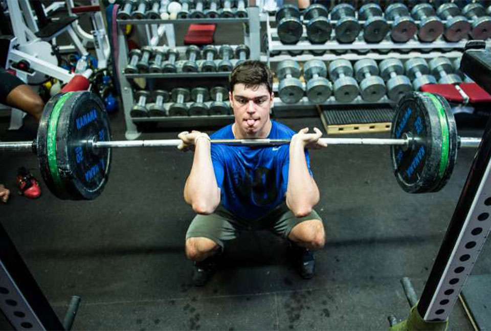 A photo of an athlete performing front squat in full range of motion.