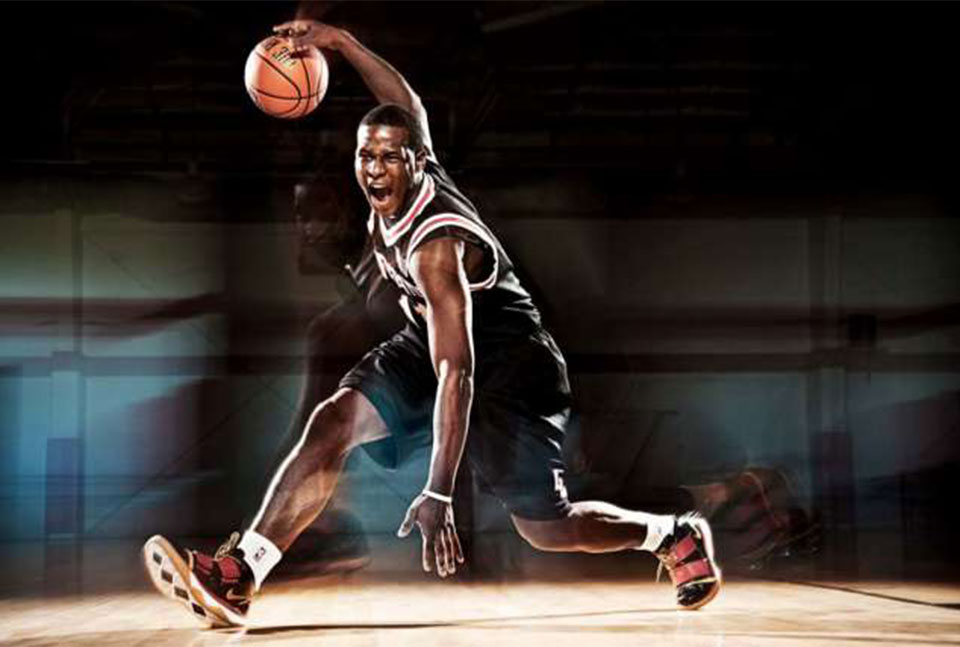 A photo of a basketball player doing some moves.