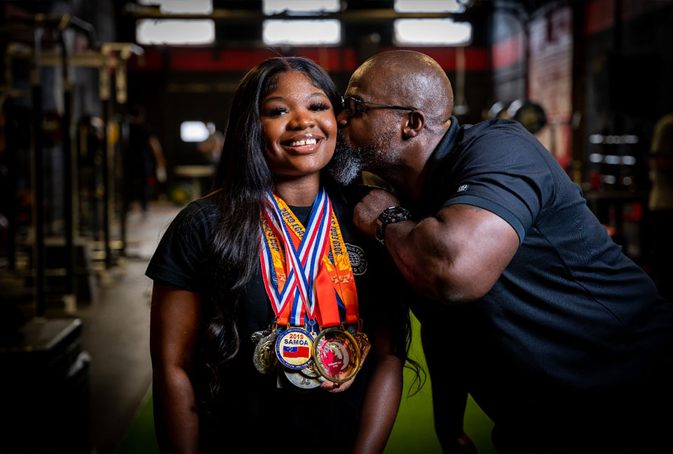 A photo of Maya Laylor wearing her medals from the Olympics with her dad Clance Laylor next to her.