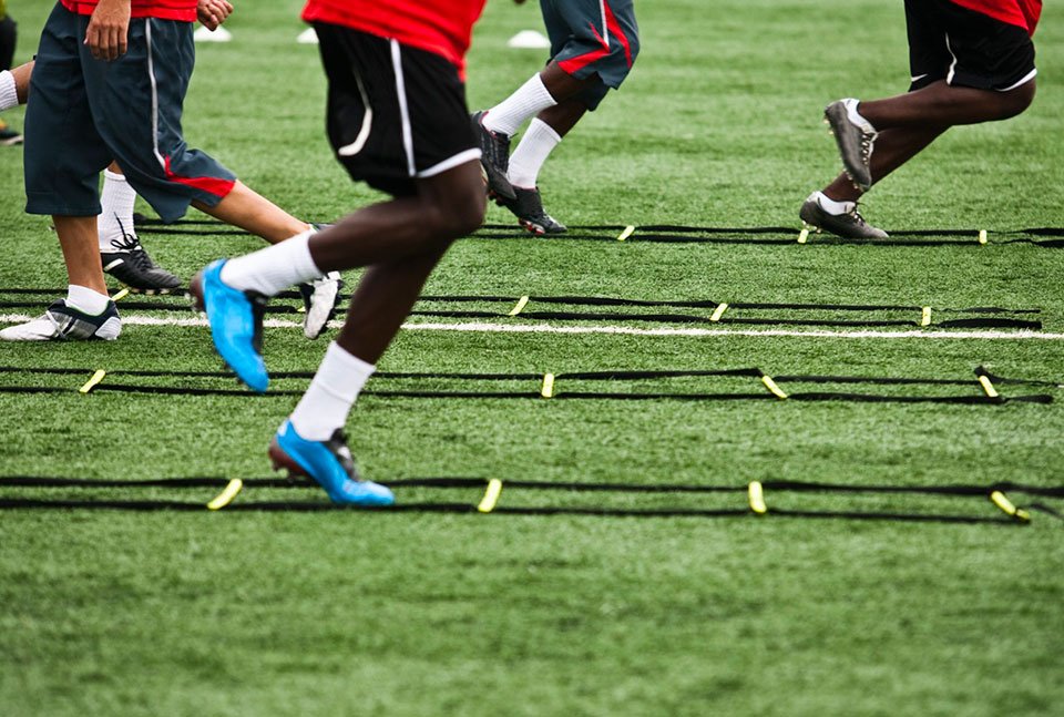 A view of athletes engaging in entertainment training using ladder drills on the game field.